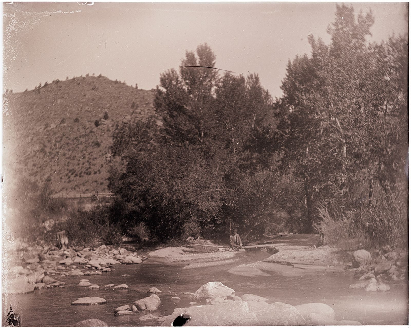 A photograph, 1903. Man taking measurements in Cache la Poudre River (Poudre River seepage trip).
